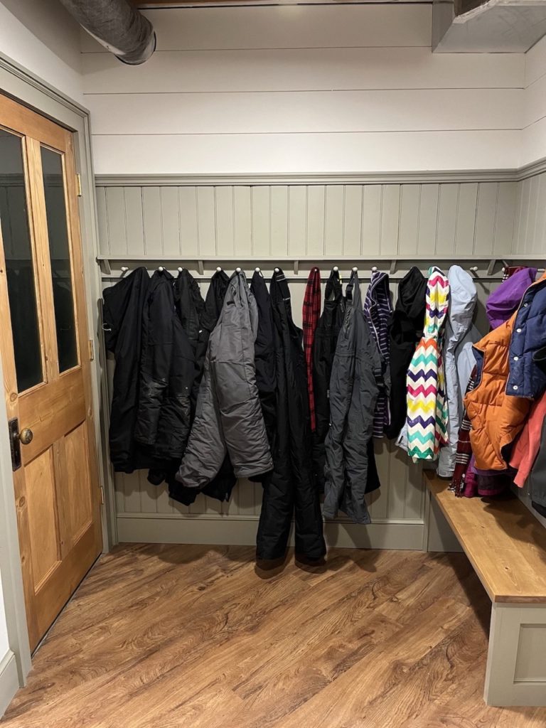 Mudroom bench with coats and gear on hooks