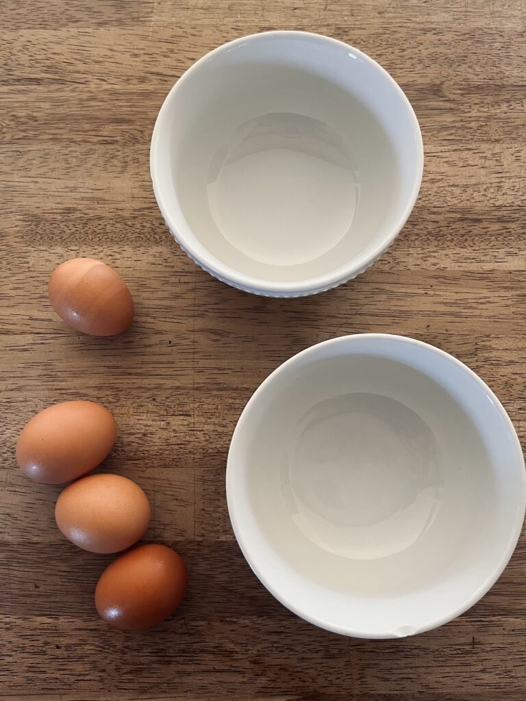 Four eggs with bowls to separate yolks and whites