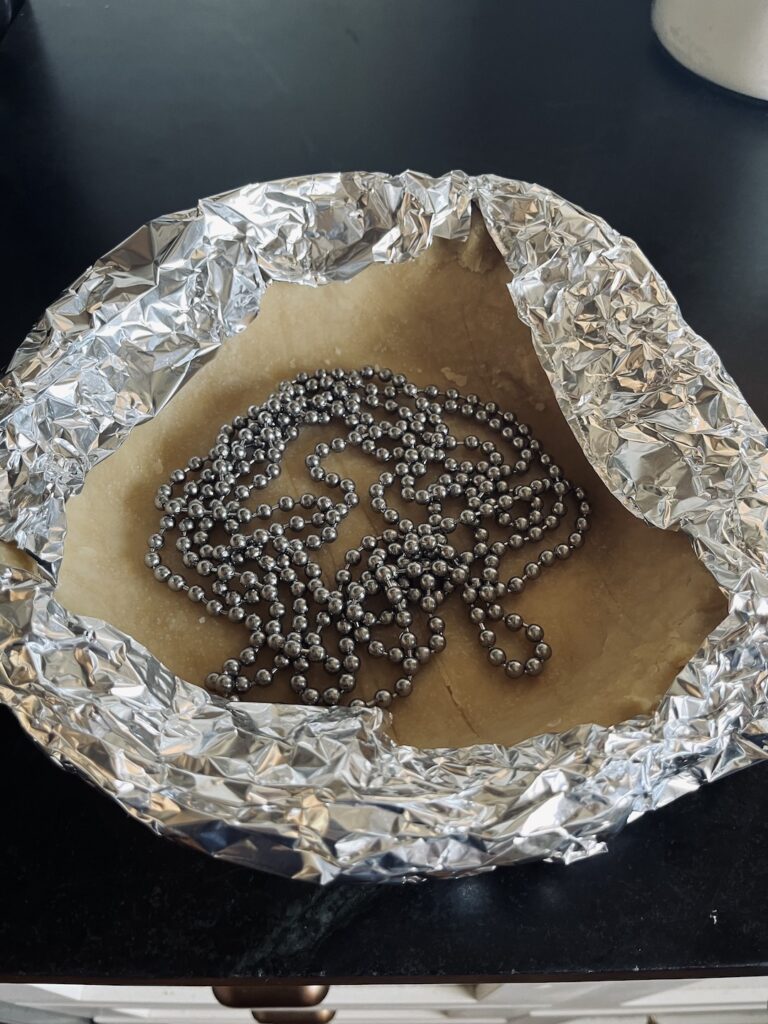 Aluminum foil around edges of pie with pie chain for weights